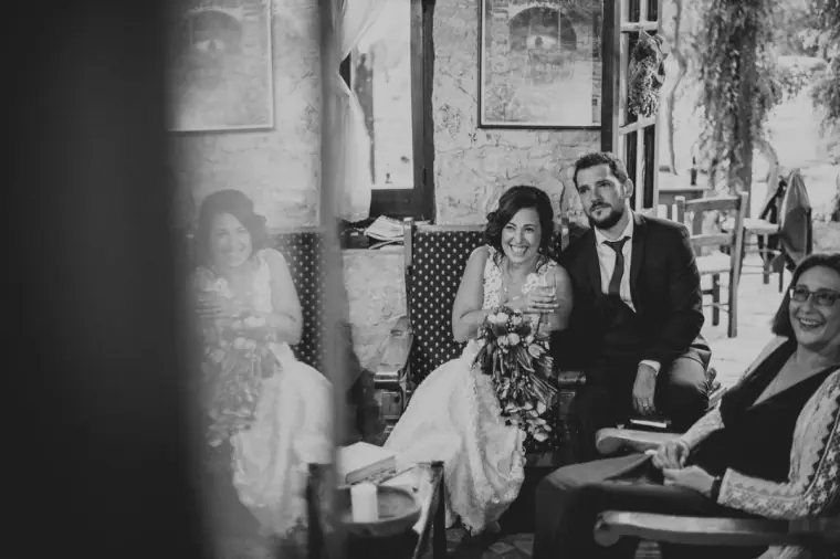 Black-and-white photo of the couple seated with guests in the inn's stone-walled lounge