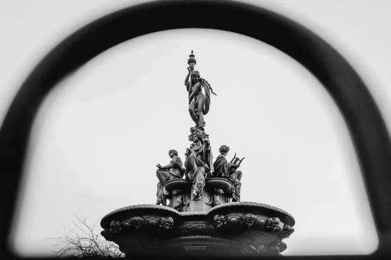 Black-and-white view of the Ross Fountain framed through an iron arch, Edinburgh
