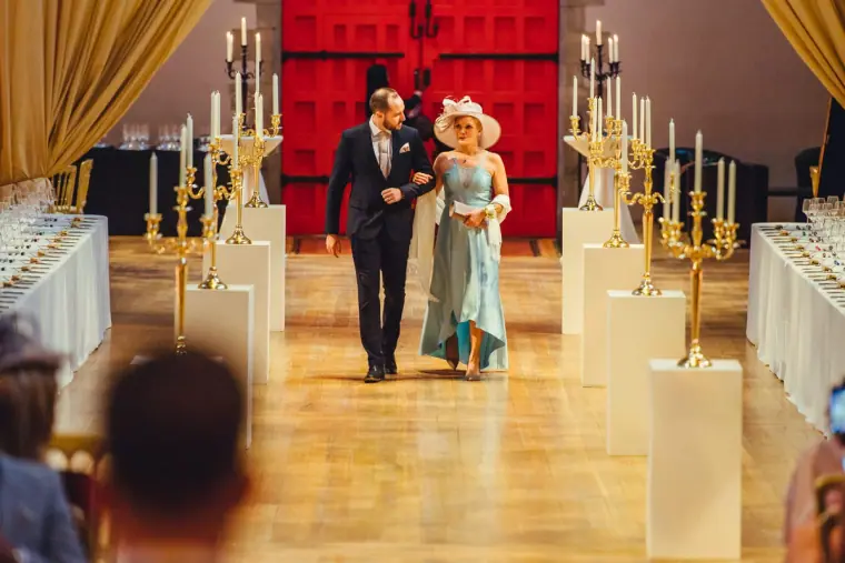 Bride walking down the aisle on her father's arm, red doors behind them