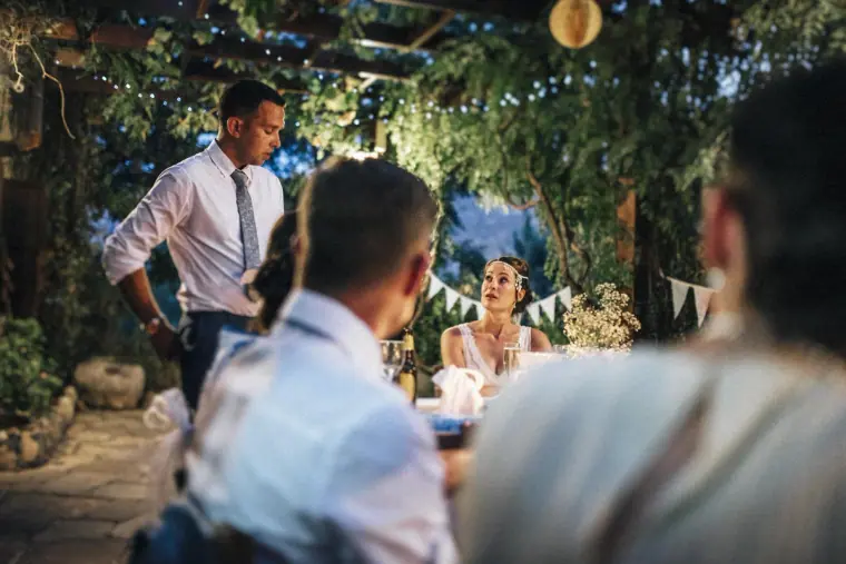 Groom standing to give his speech under fairy lights and paper lanterns