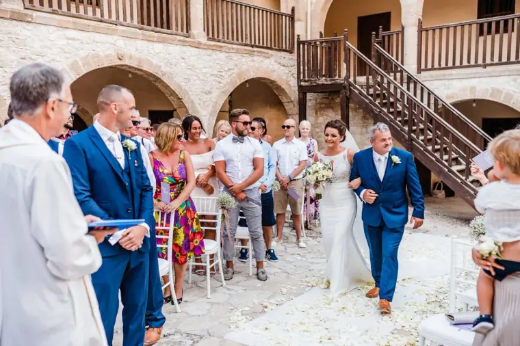 Bride walked down the petal-strewn aisle in the monastery courtyard as guests stand