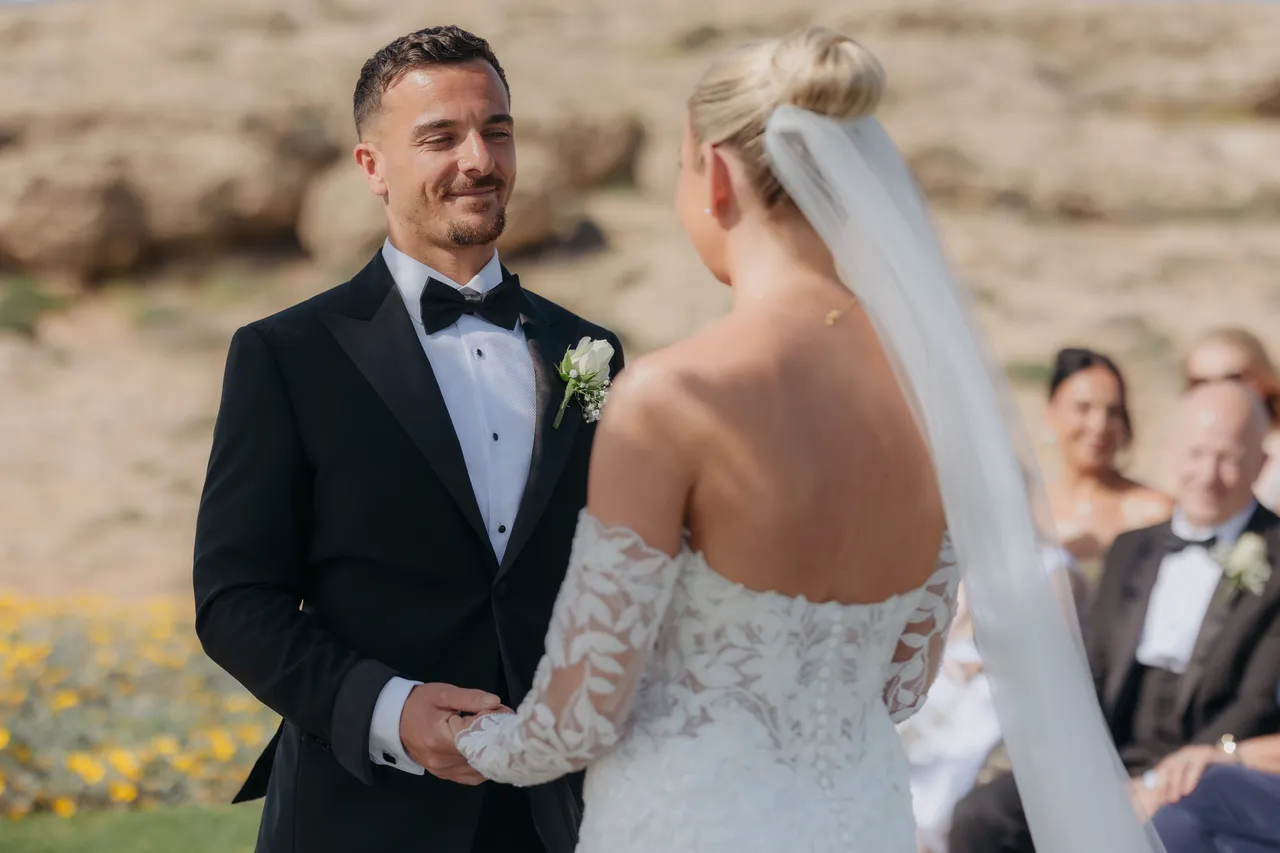 Groom smiling at his bride as they hold hands during the ceremony