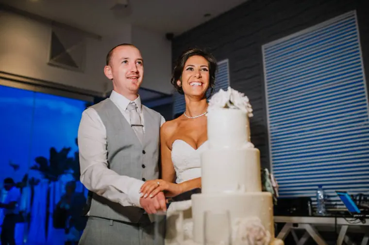 Louise and Mike cutting their three-tier white wedding cake