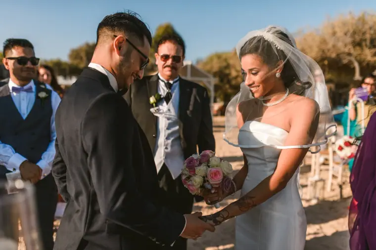 Groom seen from behind as the smiling bride reaches him at the ceremony