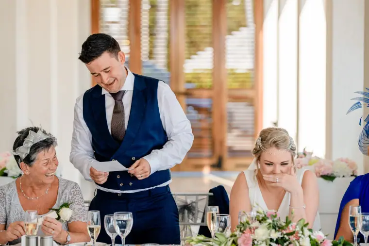 Stephen reading his groom's speech as the bride laughs beside him