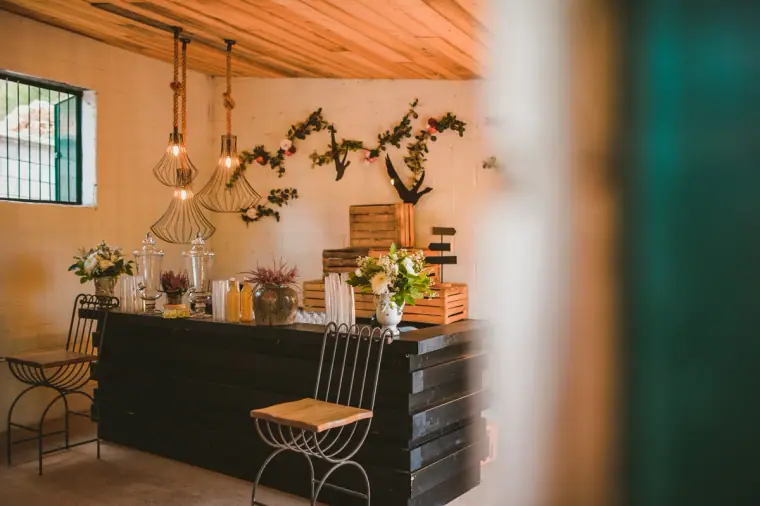 Rustic bar with hanging lights and floral garlands inside a stone building