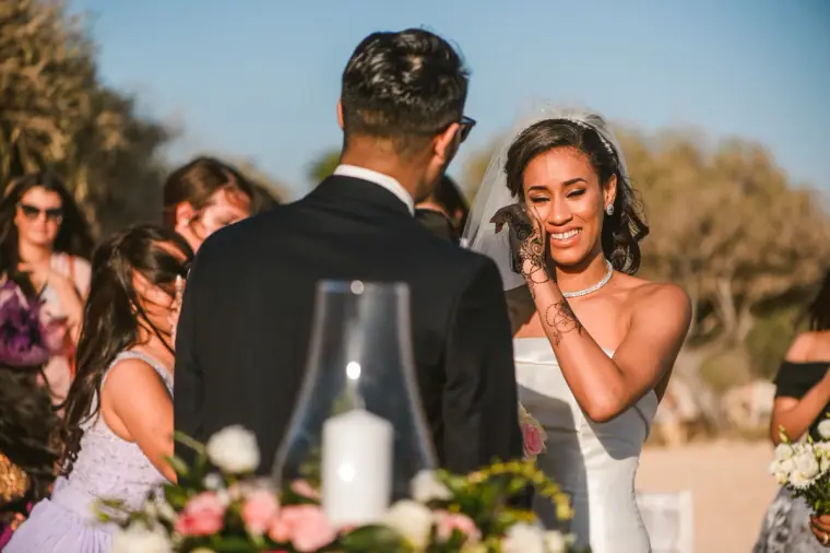 Bride laughing and brushing her hair aside as she meets the groom