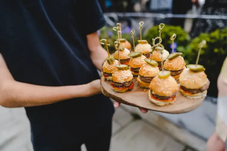 Mini burger canapés on a wooden board carried through the drinks reception