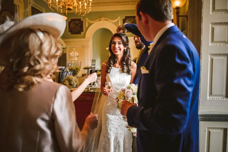Guest in a hat congratulating the smiling bride and groom after the ceremony