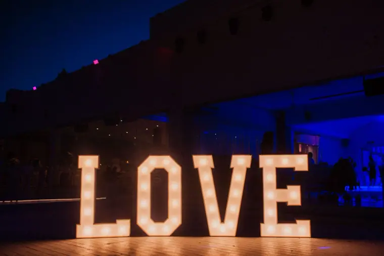 Giant light-up LOVE letters glowing on the dance floor at night