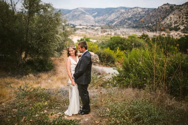 Bride and groom standing in wild scrub with hills on the horizon