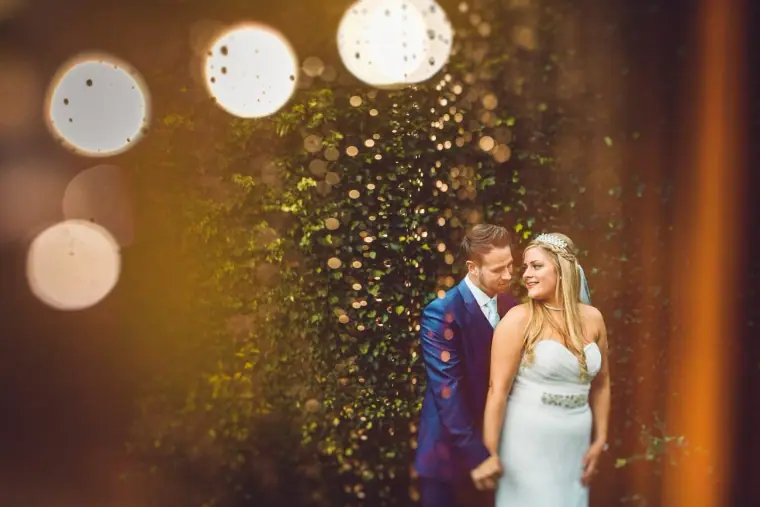 Lyndsay and Thomas framed by glittering bokeh lights at Balmer Lawn Hotel, New Forest