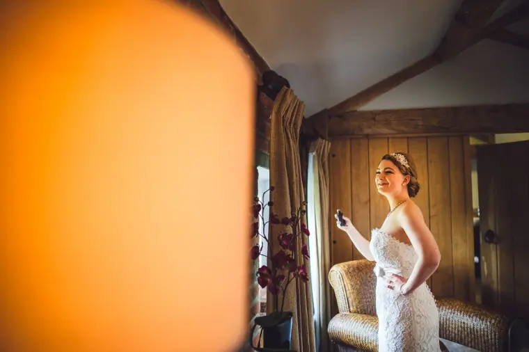 Sarah in her lace gown looking out of the window of the beamed suite