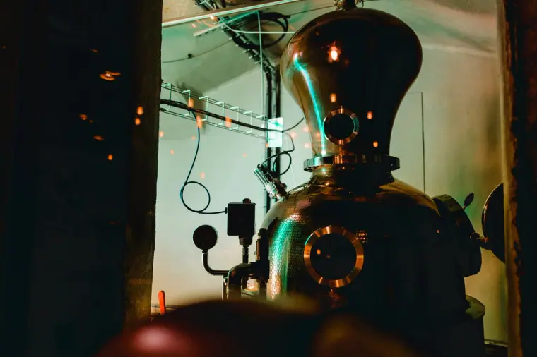 Copper gin still glowing under green light inside the Edinburgh Gin distillery