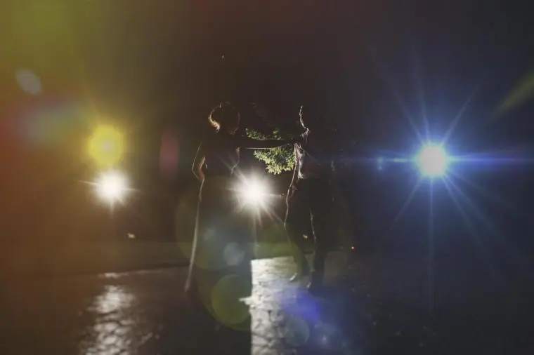Couple's first dance in the dark, lit by sparkling backlights and flare