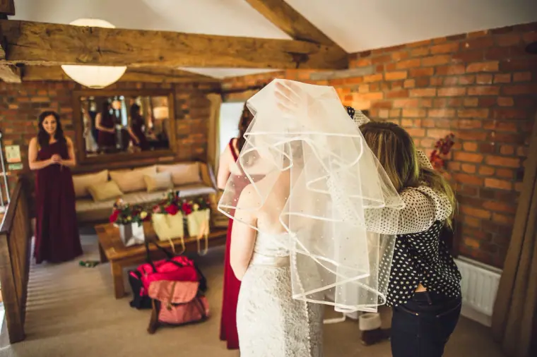 Bridesmaid fixing Sarah's veil in the brick-walled bridal suite