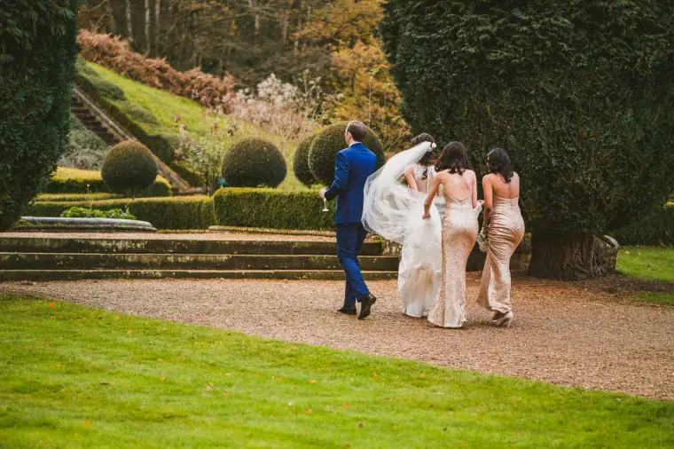 Bride and bridesmaids walking through the formal gardens at Wotton House, Dorking