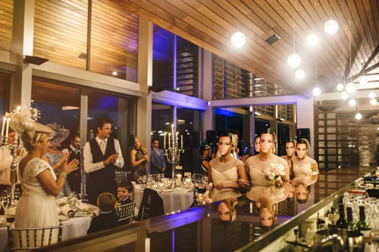 Guests in fascinators applauding as the newlyweds enter the candlelit reception