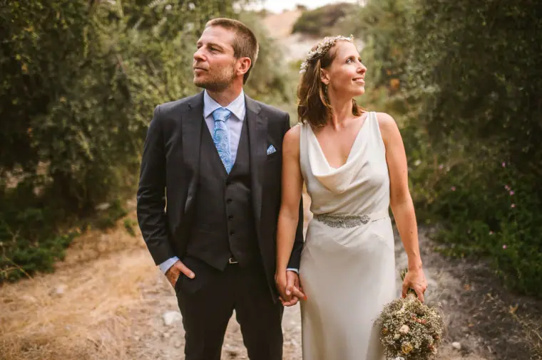 Fleur and Kazem standing hand in hand among olive trees, looking into the distance
