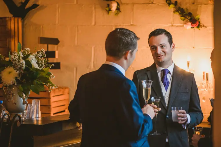 Groom chatting with a guest over glasses of fizz at the bar