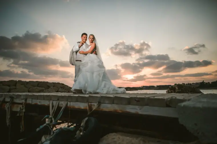 Bride and groom on a jetty under a pastel sunset sky, Coral Beach Hotel, Paphos