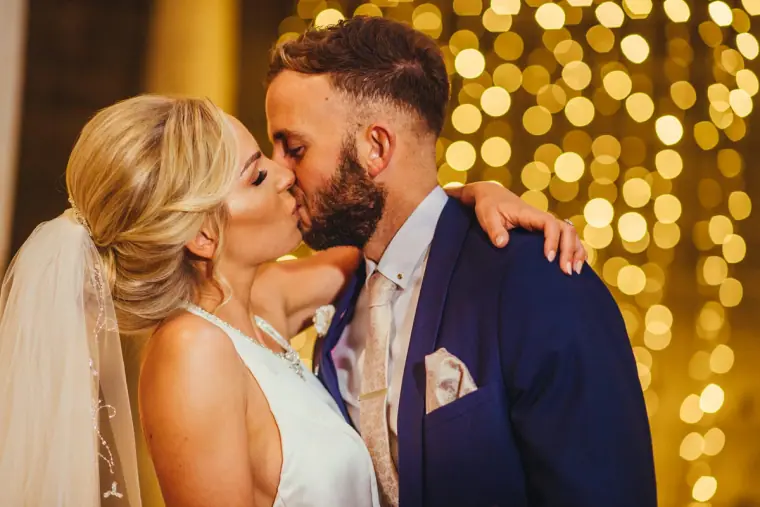 Leonnie and Andy's first kiss against a backdrop of golden fairy lights