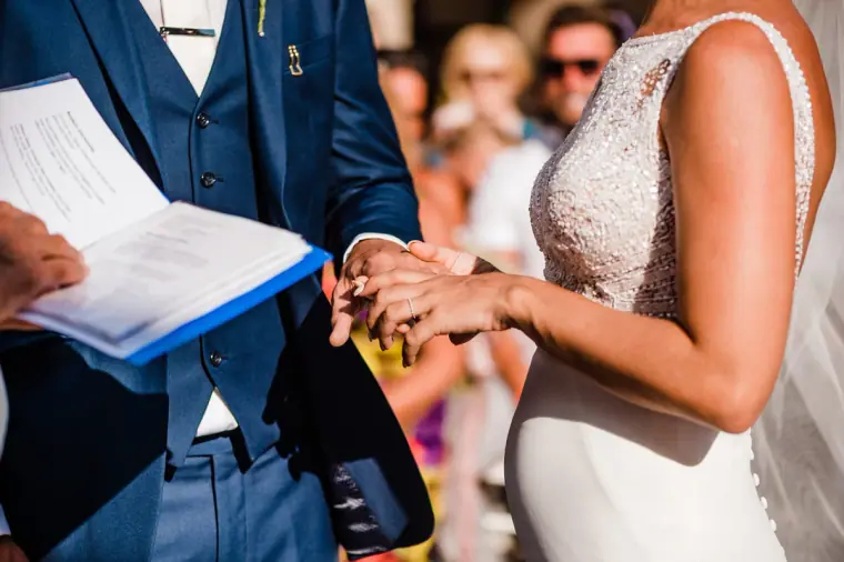 Close-up of the ring exchange as the groom holds the service booklet