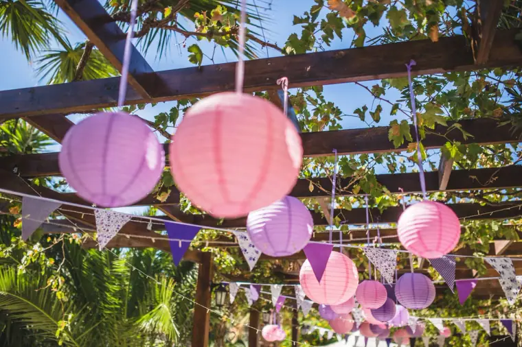 Pink and lilac paper lanterns and bunting hanging from the pergola