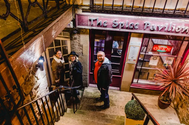 Friends standing outside The Spice Pavilion restaurant entrance in Edinburgh