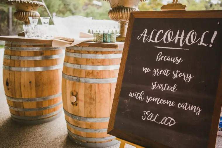 Wine barrels beside a chalkboard sign joking about alcohol and salad