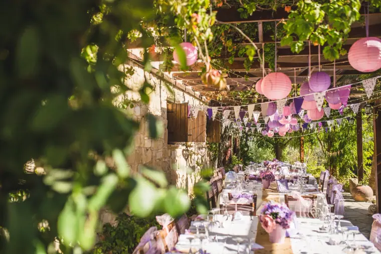 Reception tables dressed in lilac beneath lanterns under the vine pergola