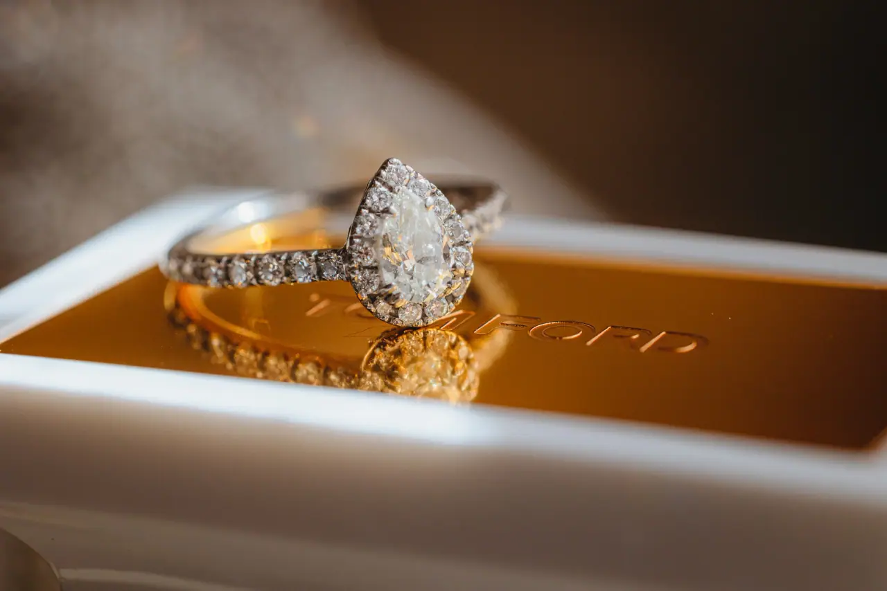Pear-cut diamond engagement ring and wedding band resting on a gold box