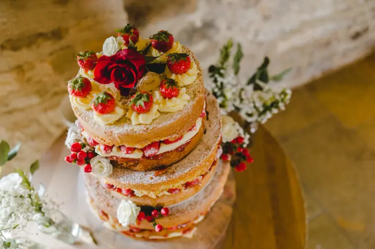 Naked sponge cake layered with cream, strawberries and red roses