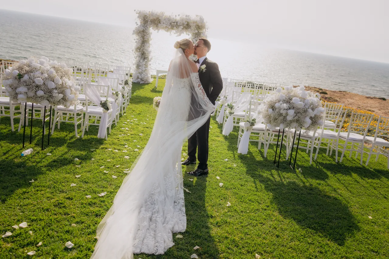 Groom lifting his bride for a kiss on the ceremony lawn overlooking the sea at Alassos