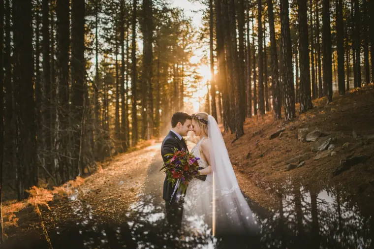 Steph and Alasdair holding a red bouquet on a sunlit forest path in the Troodos