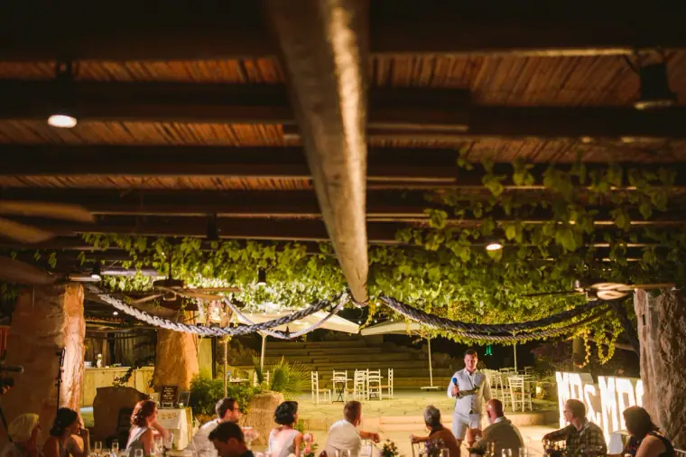 Evening reception under a vine-covered pergola with glowing letters