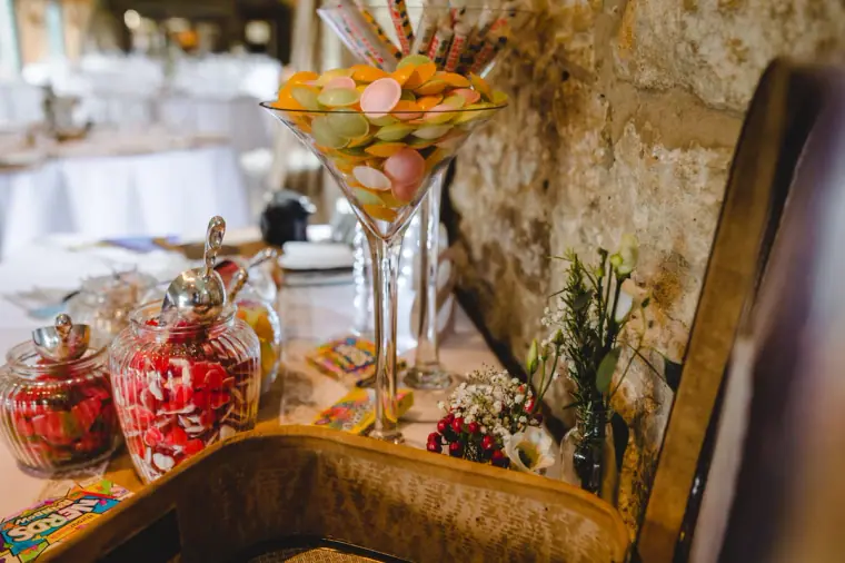 Sweet table with jars of red and pink sweets and a martini glass of candy