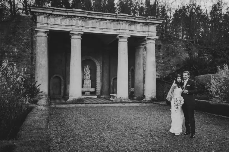 Black-and-white photo of the couple before the columned temple folly at Wotton House