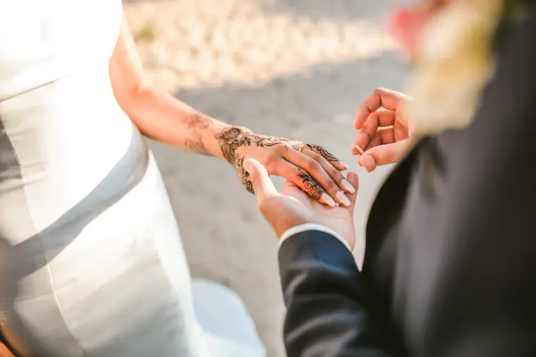 Close-up of the groom holding the bride's hennaed hand