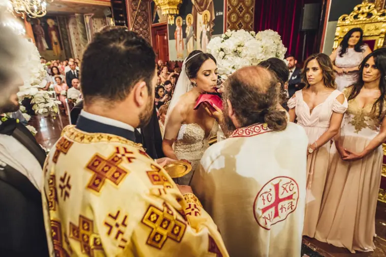 Priest blessing Ruby and Angelos as bridesmaids look on