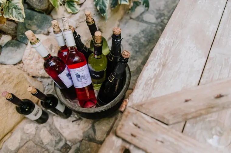 Rosé and white wine bottles chilling in a bucket on stone