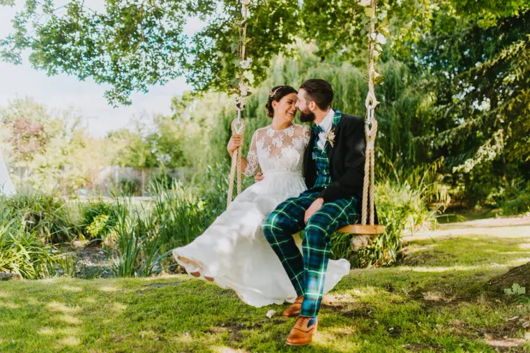 Helen and Ali sitting together on a rope swing in a green garden, Windsor