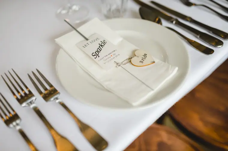 Place setting with a folded napkin, sparkler favour and wooden name tag