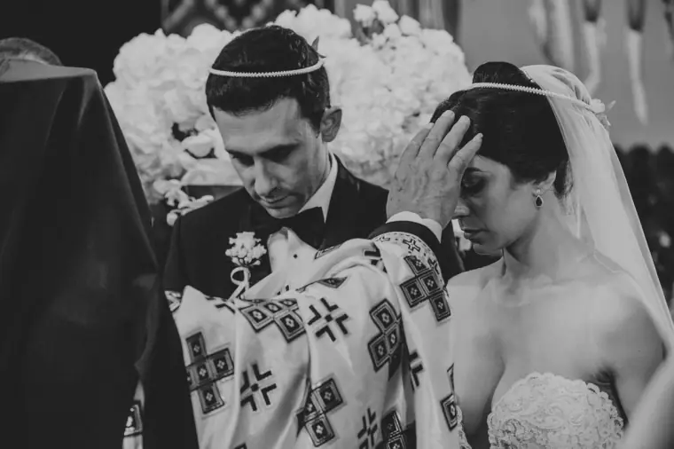Black-and-white photo of the priest blessing Ruby and Angelos during their Orthodox ceremony