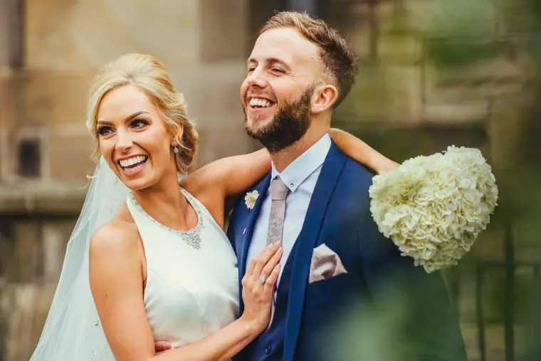 Laughing bride and groom posing with a white hydrangea bouquet