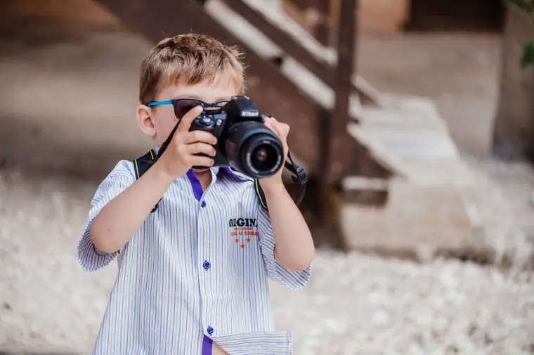 Young boy pretending to take photos with a large camera
