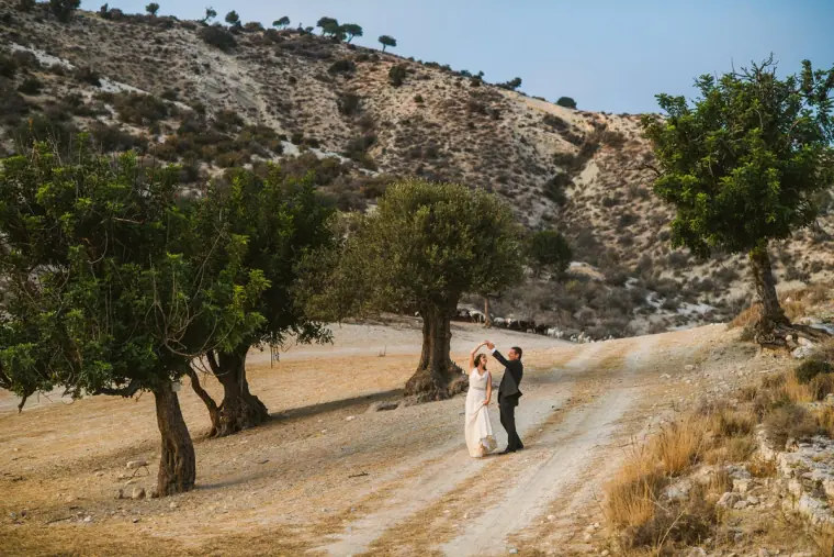 Couple embracing on a country track beneath rocky hillsides and trees