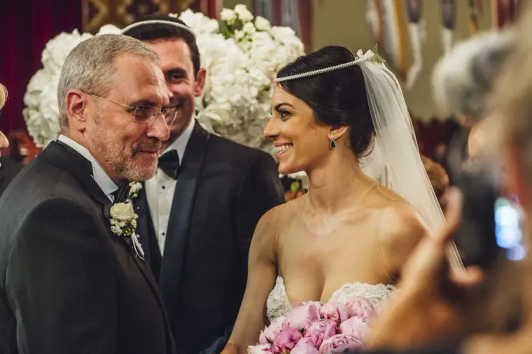 Smiling bride with pink peony bouquet greeting guests at the altar in Nicosia