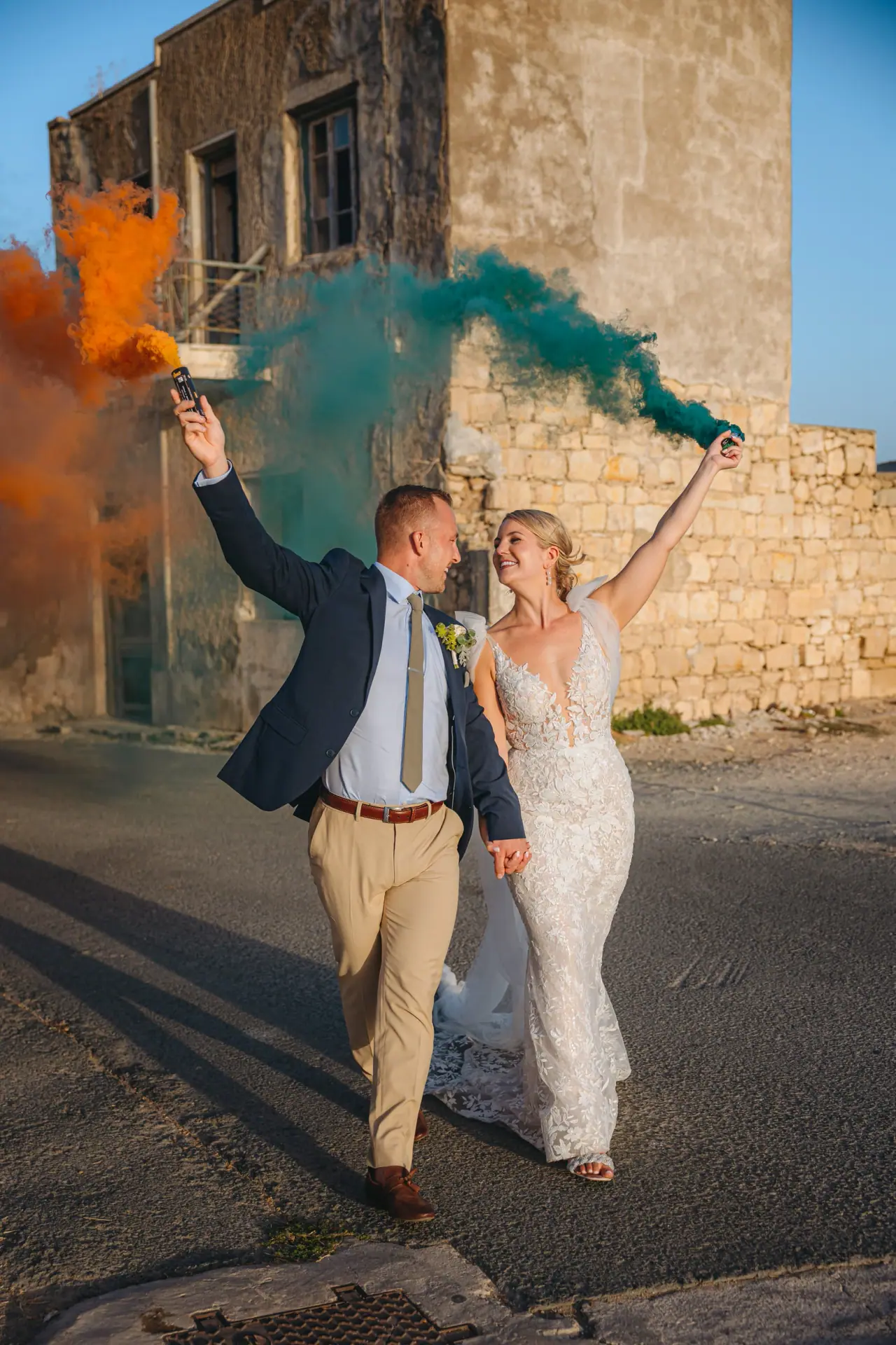 Beth and Josh walking out amid orange and teal smoke flares at Liopetro, Kouklia