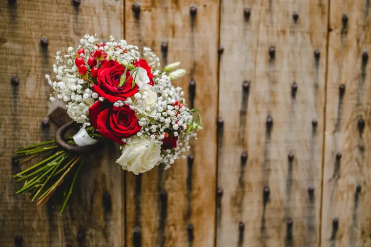 Red rose and gypsophila bouquet hanging on a weathered wooden door